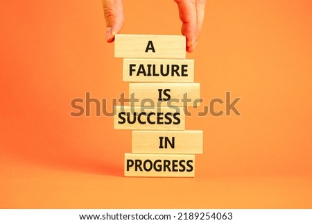 Failure or success symbol. Wooden blocks with words A failure is success in progress. Beautiful orange background, copy space. Businessman hand. Business, failure or success concept.