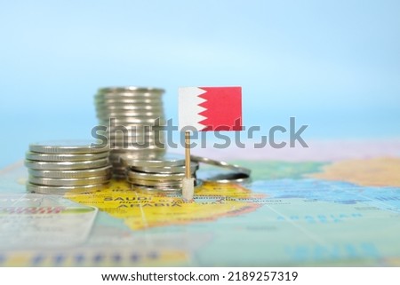 Selective focus of Bahrain flag in blurry world map with coins. Bahrain economy and wealth concept.