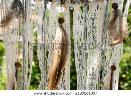 Dream catcher decorated with lace, threads, feathers and wooden beads outdoors in sunny weather