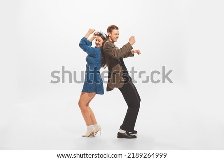 Portrait of young beautiful couple, stylish man and woman dancing at the retro party isolated over white studio background. Concept of retro fashion, style, youth culture, emotions, beauty, ad Royalty-Free Stock Photo #2189264999