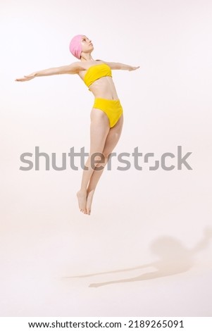 Portrait of young woman in swimming suit and cap jumping into water isolated over grey studio background. Diving. Concept of beauty, fashion, vintage style, summertime, party. Copy space for ad