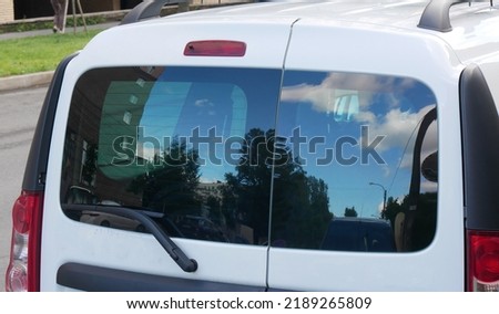 Defocused and distorted  reflection of urban landscape in rear window of car.  Red lamps, wiper, sky, clouds. Abstract view for creative design.
