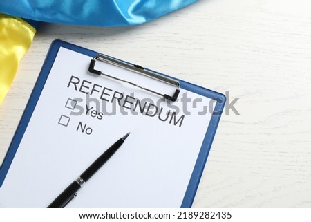 Referendum ballot with pen and flag of Ukraine on white wooden table, flat lay Royalty-Free Stock Photo #2189282435