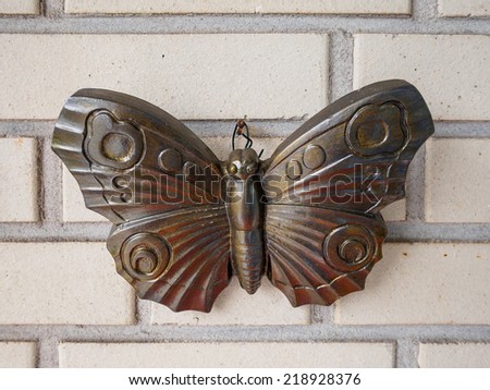Straight on view of a bronze buttefly statue on wall