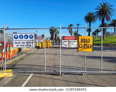 Construction site health and safety message rules signage on fence boundary - unauthorised persons keep out and protective equipment to be worn at all times.