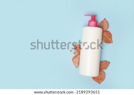 Beauty cosmetic bottle and dry autumn leaf creative still life cosmetic photography, blue background with copy space