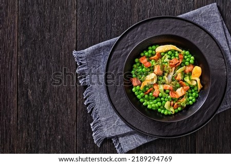 petits pois, french dish of tender, new-season peas braised in chicken stock with lettuce, onion bulbs and speck, cut into lardons,  served in bowl, horizontal view from above, flat lay, free space