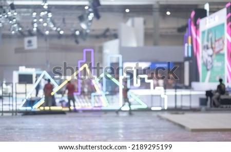 Blurry workers preparing exhibition event hall. Bokeh background of trade show business, world or international expo showcase, tech fair, with exhibitor trade show booth displaying product. Royalty-Free Stock Photo #2189295199
