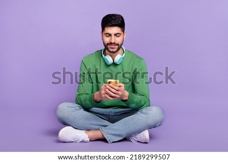 Full size photo of cheerful positive optimistic guy wear green pullover chatting typing comment post isolated on violet color background