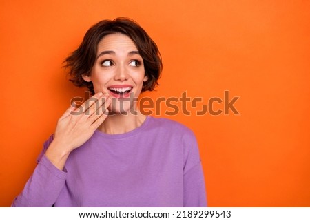 Photo of impressed cheerful girl hand near mouth look interested empty space isolated on orange color background