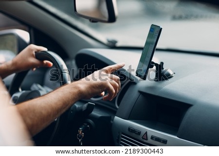 Navigator map in car vehicle transportation commuter. Driver man pointing hand finger mobile phone navigator app while driving car Royalty-Free Stock Photo #2189300443