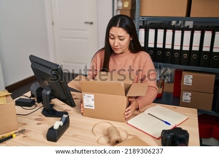 Young latin woman working at small business ecommerce skeptic and nervous, frowning upset because of problem. negative person. 