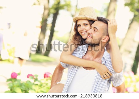 A picture of a romantic couple doing piggyback in the park