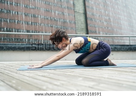 Young attractive woman doing stretching yoga exercise in the park.