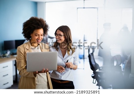 Happy multiethnic business women working together online on a laptop in corporate office. Royalty-Free Stock Photo #2189325891