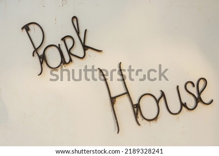 The inscription "Park" and "house" on a white wall. Iron bar inscriptions. Decoration on the handmade house
