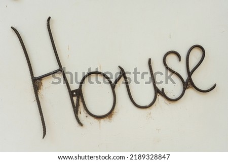 The inscription "house" on a white wall. Iron bar inscriptions. Decoration on the handmade house