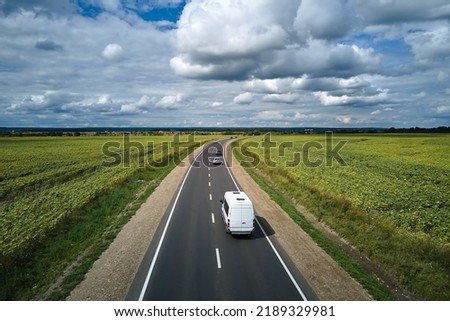 Aerial view of intercity road between green agricultural fields with fast driving cars. Top view from drone of highway traffic Royalty-Free Stock Photo #2189329981