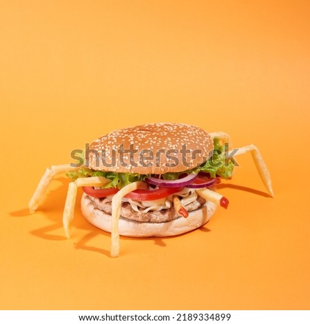 Burger with juicy marbled beef patty, freshly baked bun, fresh farm vegetables, melting cheese and signature sauce. Burger with French fries on the orange background. Side view.