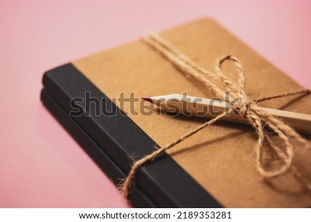 A beauty eco notepad for notes, tied with sacking rope bow. Wooden pink pencil for personal journal entries. Girly, feminine secrets. Accessories for studying, drawing, working, female planning.  Royalty-Free Stock Photo #2189353281