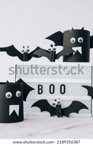 Lightbox with text BOO around paper bats. Halloween party decoration. Greeting card for autumn holiday Treat or trick