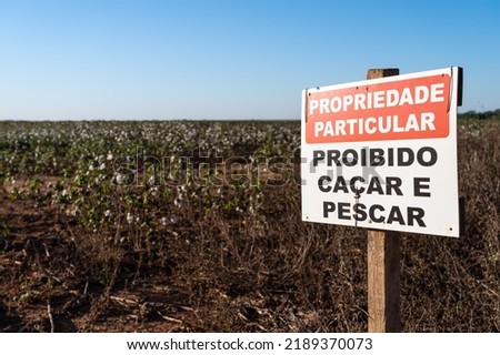 "No hunting and fishing, private property" sign on cotton, corn and soybean farm on BR-163 road. Mato Grosso, Brazil. Concept of agriculture, ecology, environment, security, law, industry.
