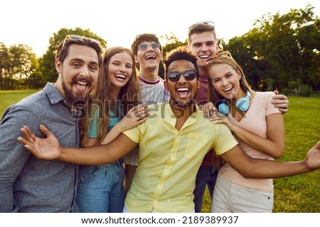 Group of young diverse people enjoy free time in summer, meet up in the park and have fun all together. Bunch of six happy excited multi ethnic friends looking at the camera, smiling and laughing Royalty-Free Stock Photo #2189389937