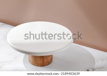 White empty Cake stand, Bakery utensil and dishware. Podium for cake. Minimalist mockup for cake with window shadow. Design Template. Front diagonal view Royalty-Free Stock Photo #2189403639