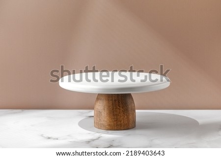 White empty Cake stand, Bakery utensil and dishware. Podium for cake. Minimalist mock up for cake with window shadow. Design Template. Front view. Royalty-Free Stock Photo #2189403643