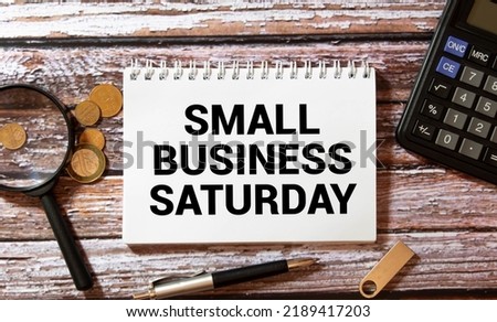 Text Small Business Saturday in notebook on white table with office tools. Royalty-Free Stock Photo #2189417203
