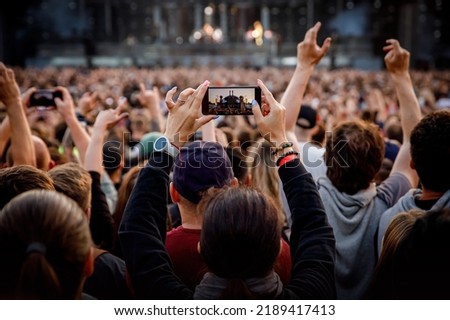 Smartphone in the hand of a music fan at the summer concert Royalty-Free Stock Photo #2189417413