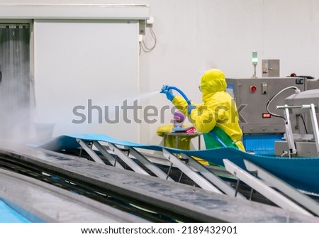 Worker use high pressure water spray cleaning conveyor belt in chicken meat process. Royalty-Free Stock Photo #2189432901