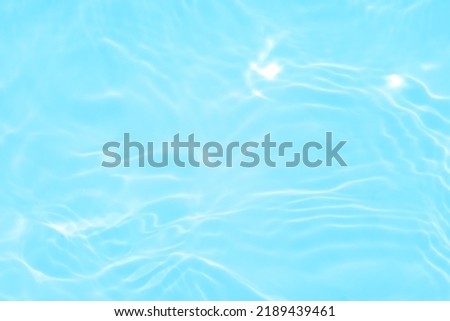Defocus blurred transparent blue colored clear calm water surface texture with splashes and bubble. Trendy abstract nature background. Water wave in sunlight with copy space. Blue watercolor texture