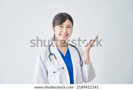 Asian female doctor pointing side in white background Royalty-Free Stock Photo #2189452141