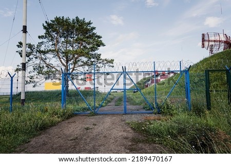The restricted area is fenced with a metal fence, gates and barbed wire.