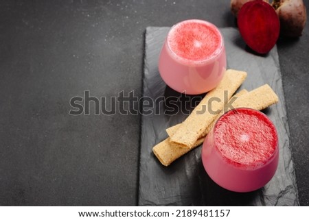A cup of hot beet coffee latte on a light wooden background. A trendy, healthy drink. An alternative to caffeine. Beet latte on a dark background. Top view and copy space.