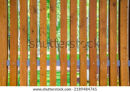 The fence is made of vertical wooden boards.