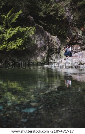 Man Photographs Nature Photo

A photographer takes a knee to take a pictures of clear water from a rock. Nature 