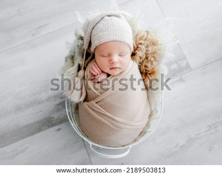 Newborn baby child swaddled in fabric sleeping in basket. Sweet infant kid napping portrait Royalty-Free Stock Photo #2189503813