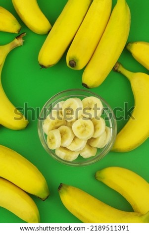 Sliced in bowl and whole bananas on green background