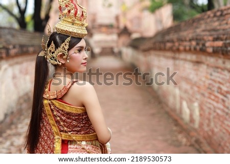 Rear view fashion and beautiful asian woman wearing Thai red traditional costume holding jasmine garland with happy and peace standing outdoor in ancient temple Ayutthaya, Thailand. Travel concept