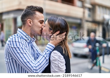 Man and woman couple hugging each other kissing at street