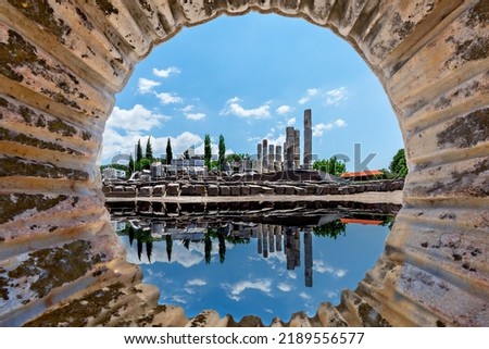 Ruins of the sanctuary of Apollon Smintheus and its reflection in the puddle through the carved out marble column in Ayvacik, Turkey. Royalty-Free Stock Photo #2189556577