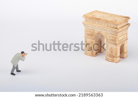 miniature figurine of a photographer taking pictures of an ancient arch 