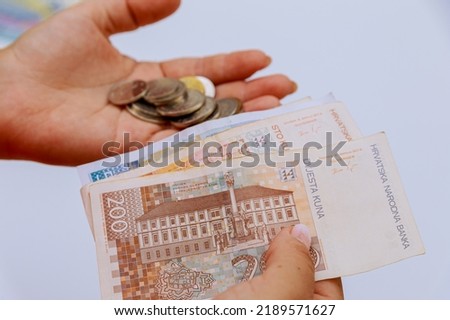 Croatian kuna and coins lipa in the hands of a woman on a white background. Royalty-Free Stock Photo #2189571627