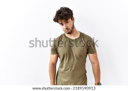 Hispanic man standing over isolated white background looking sleepy and tired, exhausted for fatigue and hangover, lazy eyes in the morning. 