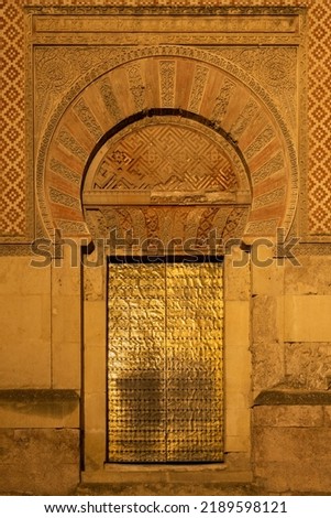 Street view of a golden door on the Mezquita facade at night. The Mosque–Cathedral of Córdoba is an Unesco world heritage site. Long exposure image.