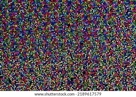 Multicolored sequins on black fabric. Background texture.