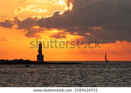 View of the island of Formentera harbor and its lighthouse at sunset with sailboats sailing by. Travel and tourism concept Royalty-Free Stock Photo #2189626931