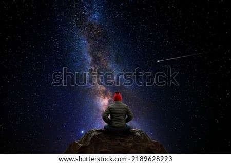 Man sitting on top of a mountain, observing the universe